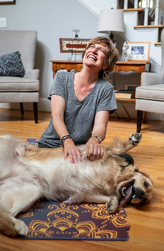 Karen J Hardwick laughing while sitting on the floor with her golden retriever
