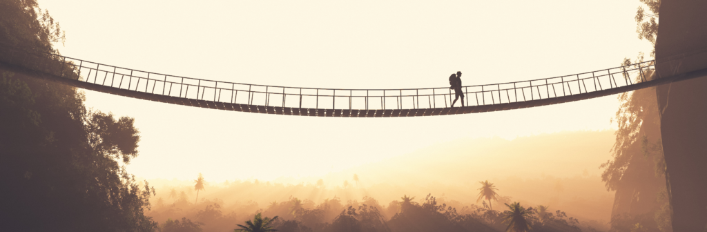 Person on rope bridge between mountains