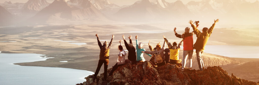 Group of people with arms raised on mountain top