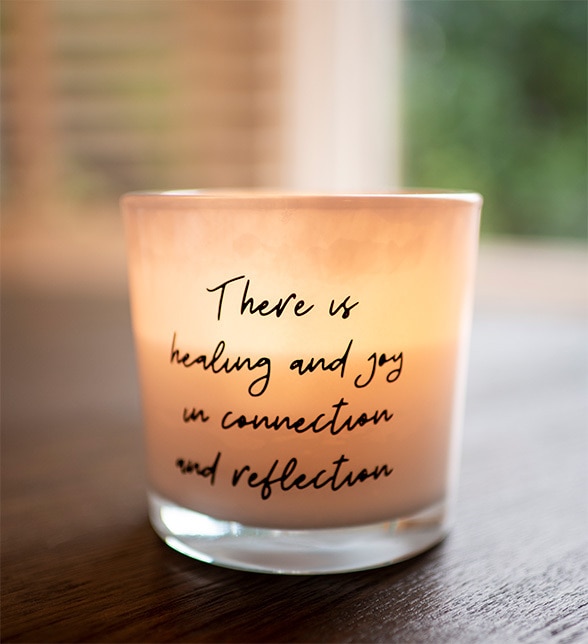 A candle with the inscription, "there is healing and joy in connection and reflection."
